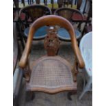 Most unusual cane seated oval backed armchair in mixed woods with ornate carved single splat to
