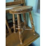 Circular dished seated joint stool on 4 splayed turned legs united by cross stretchers