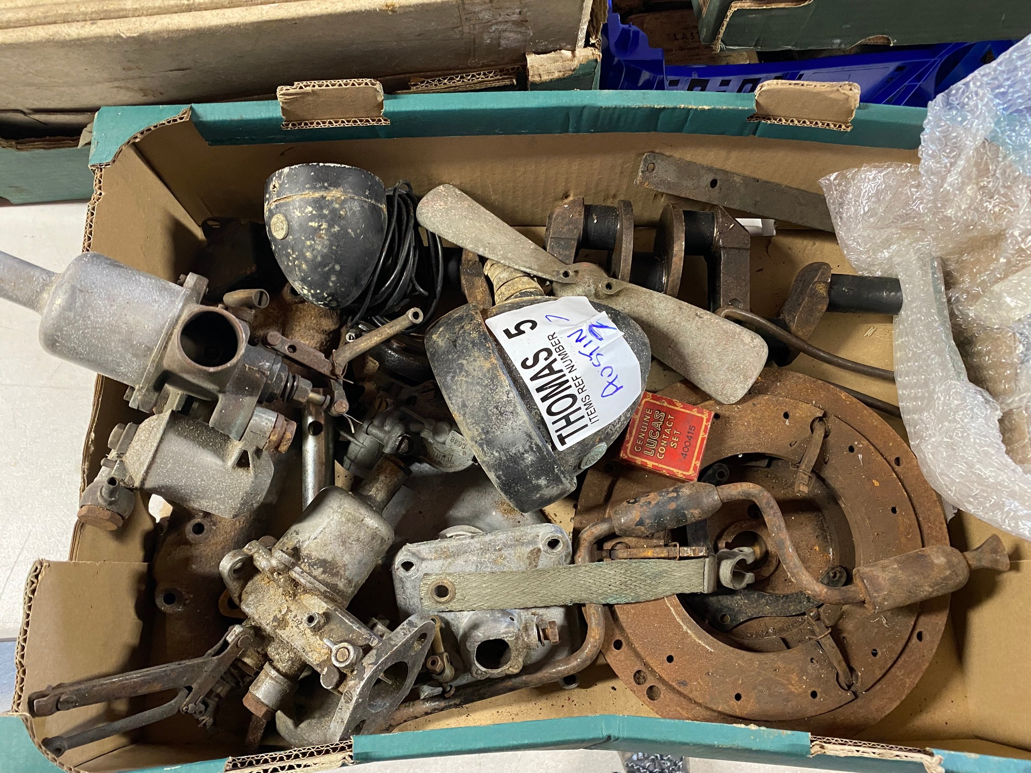 A box of Austin 7 parts including lamps, carburettors, manifold, clutch etc.