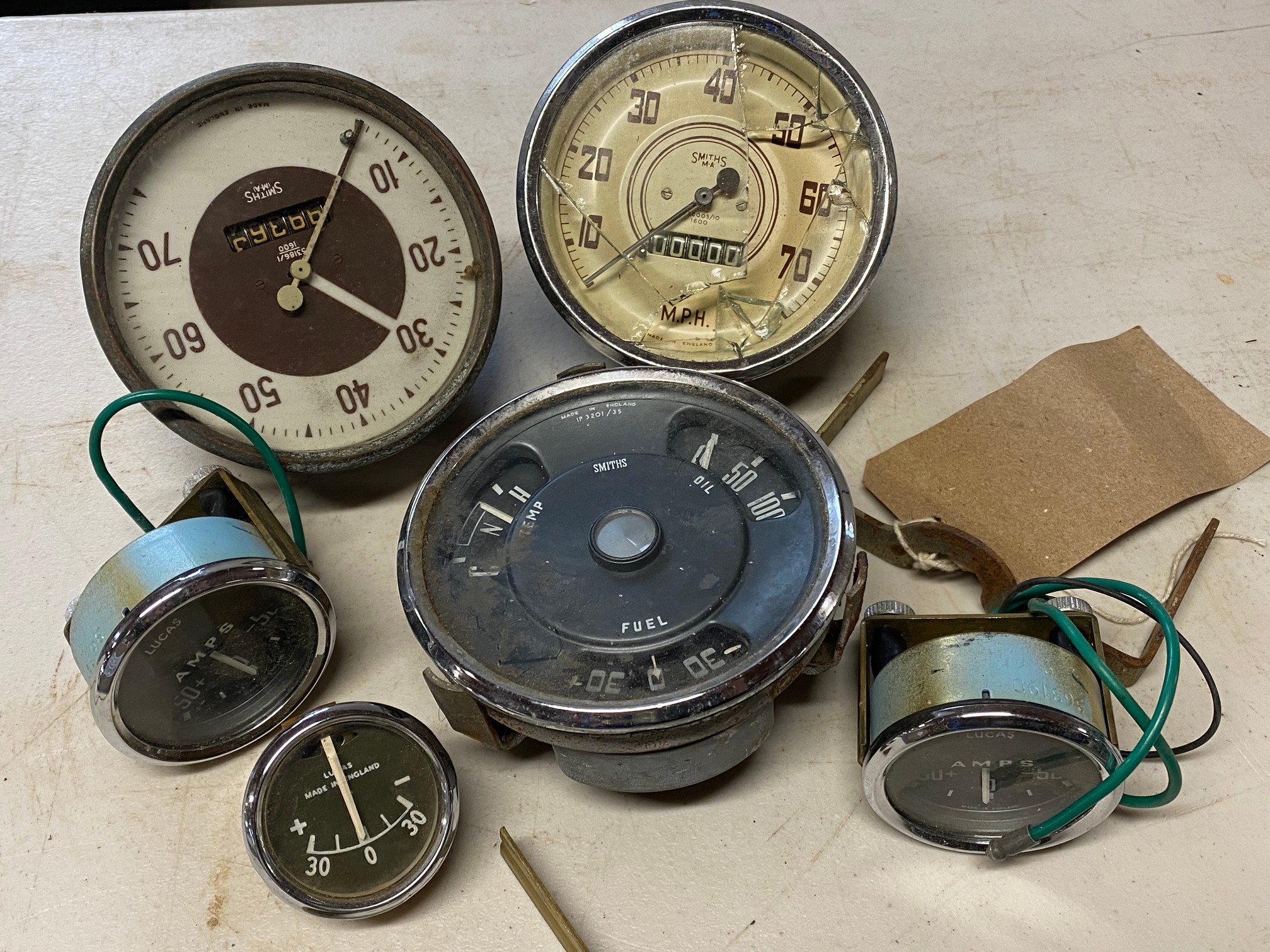 Three black faced ammeters, appear new old stock, two 0-70 mph speedometers plus a combined gauge.