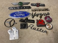 A small box of car insignia and badges including Mini, Austin, Jaguar and Ford.
