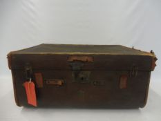 A tan leather and brown canvas covered travel trunk.