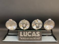 A group of four Lucas spot lamps on a dealership display stand, with a Lucas 'King of the Road'