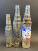 An Esso Extra quart oil bottle and two Essolube glass oil bottles.