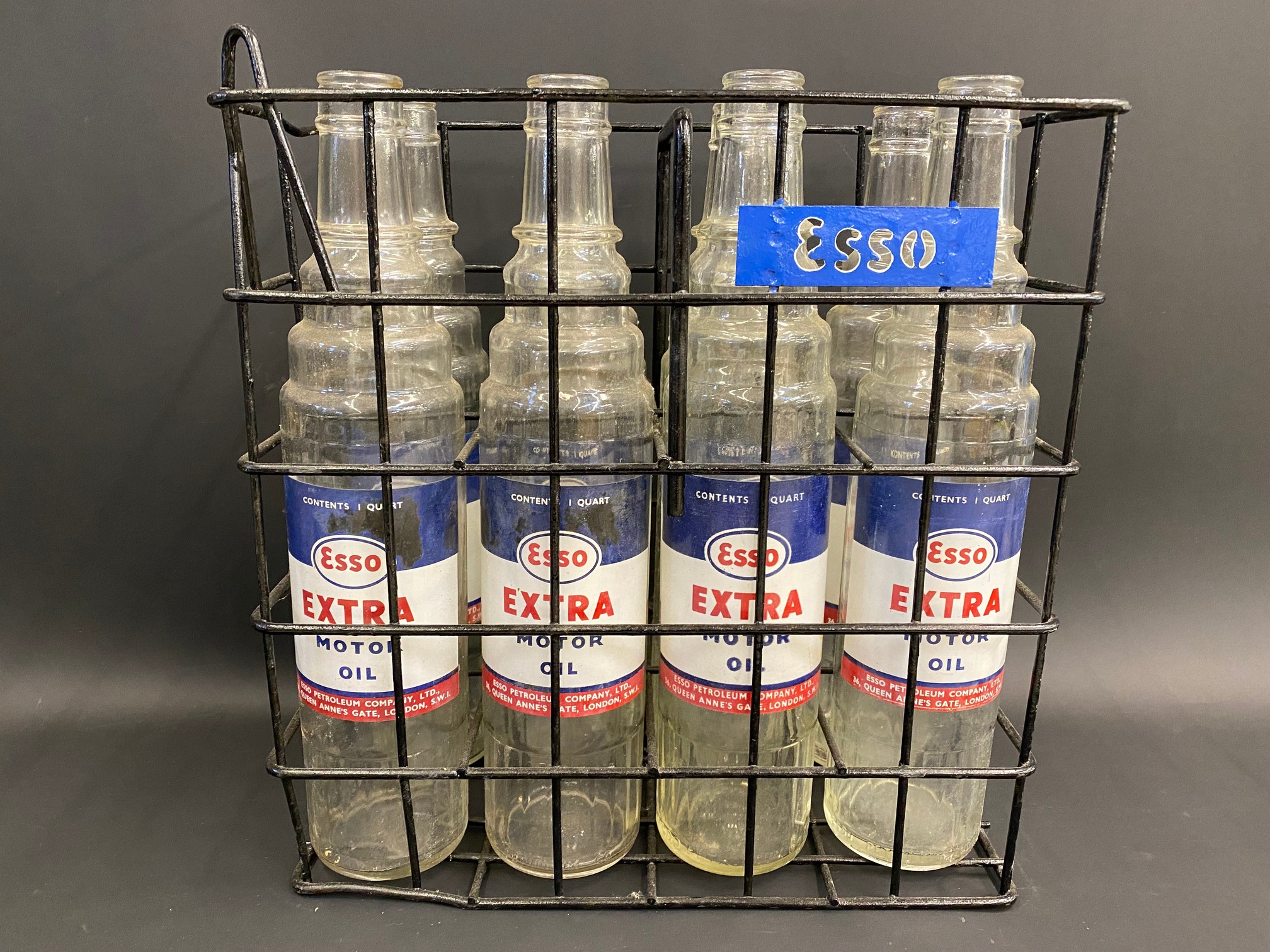 A set of eight Esso Extra Motor Oil glass quart oil bottles, with good labels, in a carrying crate.