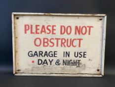 A wooden garage forecourt sign bearing the words 'Please do not obstruct garage in use day and