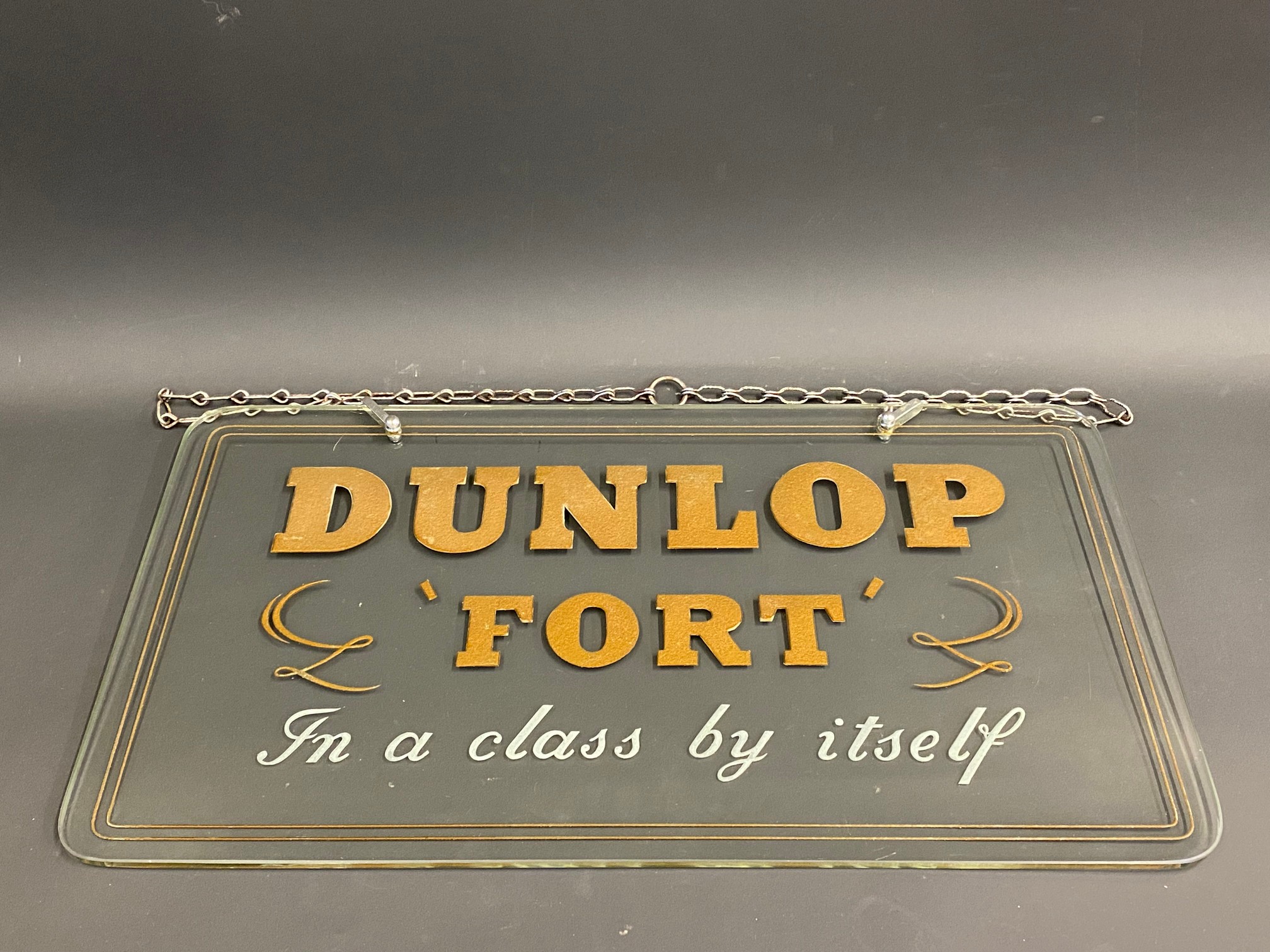 A Dunlop Fort glass showroom sign with reverse etched gilded letters, and hanging chain, 22 x 12".