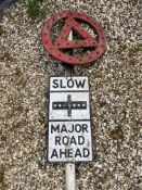 A metal road sign mounted on a tall post, surmounted by a warning triangle in a circle with integral