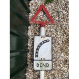 A metal road sign for Bend with integral glass reflective discs, mounted on a tall post,