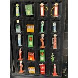 A group of die-cast miniature petrol pumps and oil cabinets, in a sectional cabinet for display.