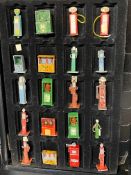 A group of die-cast miniature petrol pumps and oil cabinets, in a sectional cabinet for display.