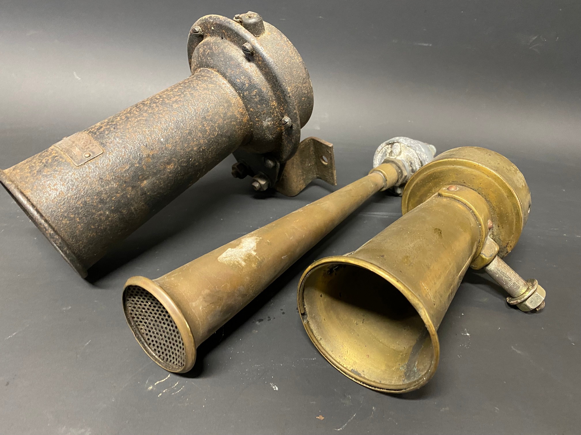 A Bosch electric horn, a Lucas polished brass horn and one other.