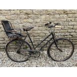 A ladies Raleigh bicycle with Brooks leather saddle and toddler chair to the rear.