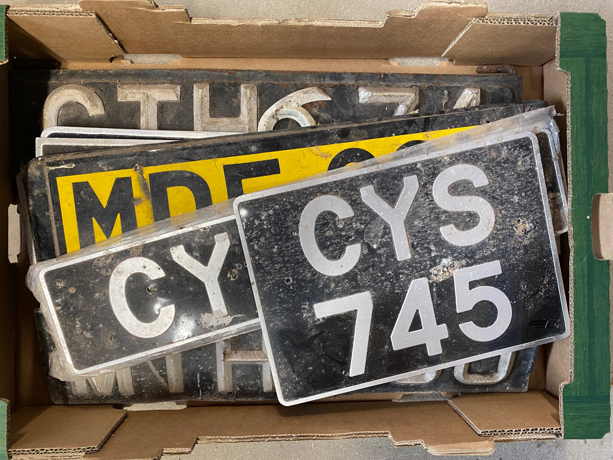 A box of assorted old number plates.