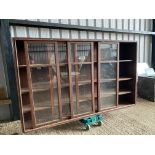 A large stained pine display cabinet with five sliding glass doors, 89 1/4" w x 54 1/2" h x 14 1/