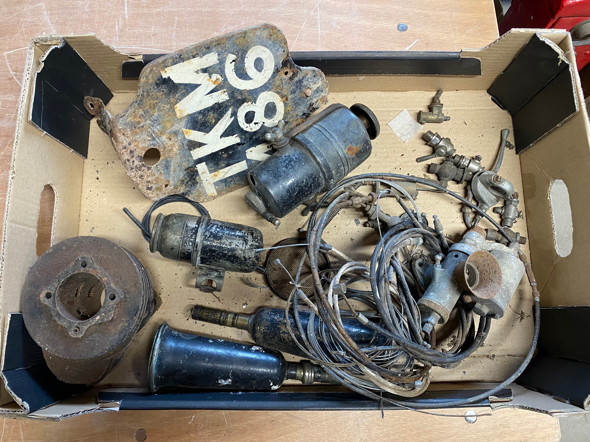 A box of assorted motorcycle spares including taps, generators, rear number plate etc.