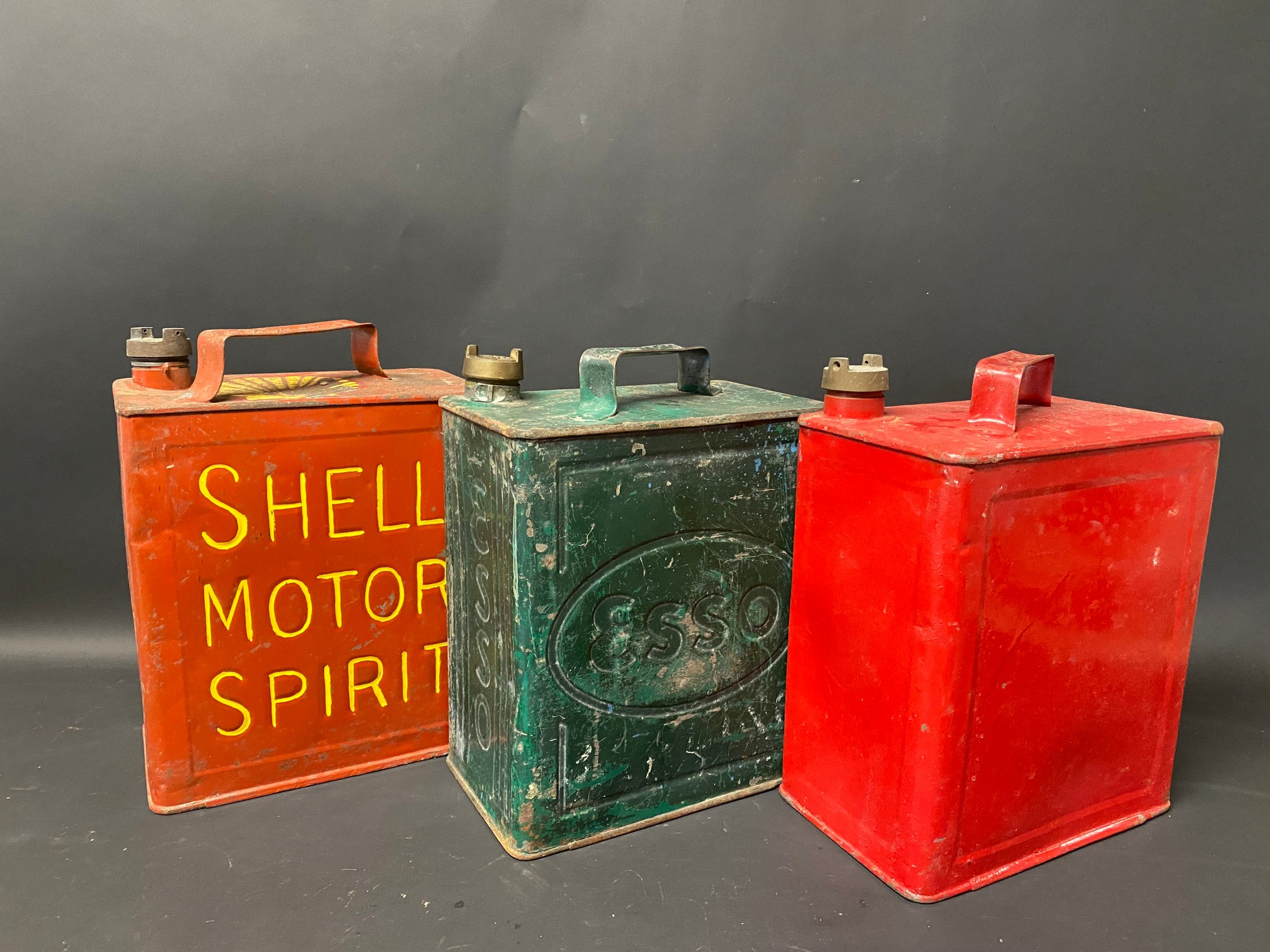 Three two gallon petrol cans for Shell Motor Spirit, Esso and one other.