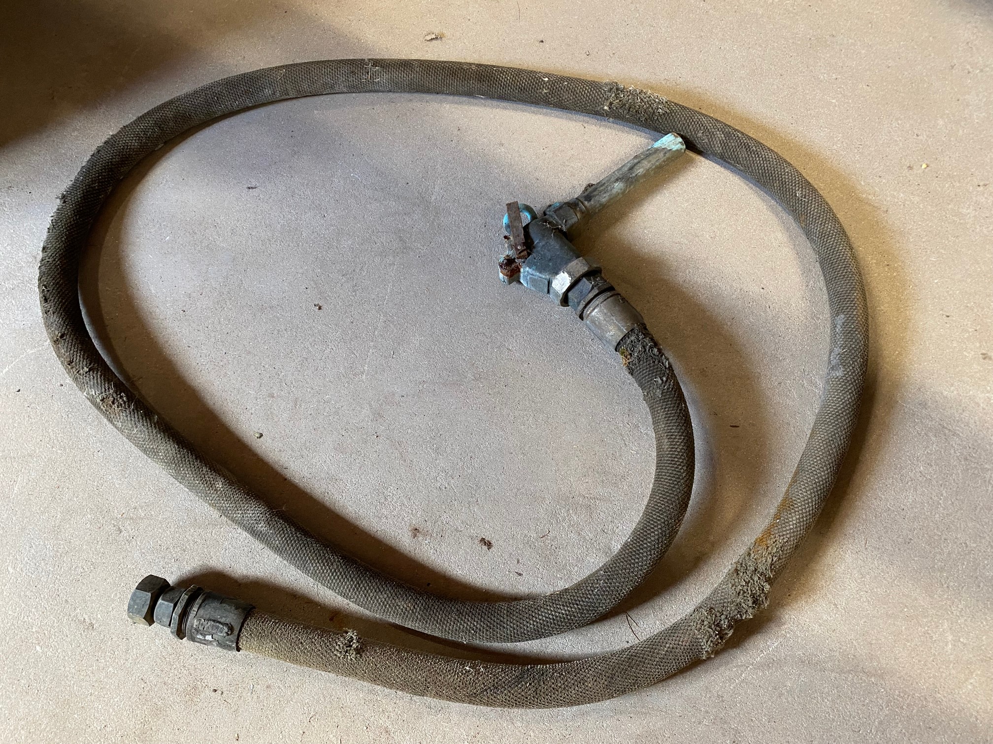 A canvas petrol pump hose with brass nozzle.