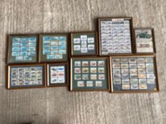 A collection of framed and glazed groups of motoring themed cigarette and trade cards.