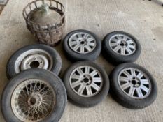 A set of four Ford alloy wheels, a wire wheel, a pressed steel wheel and a glass battery acid
