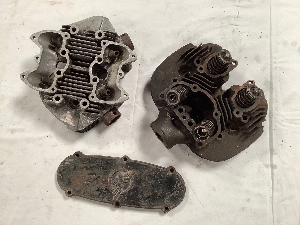 Two cylinder heads and a Matchless timing cover.