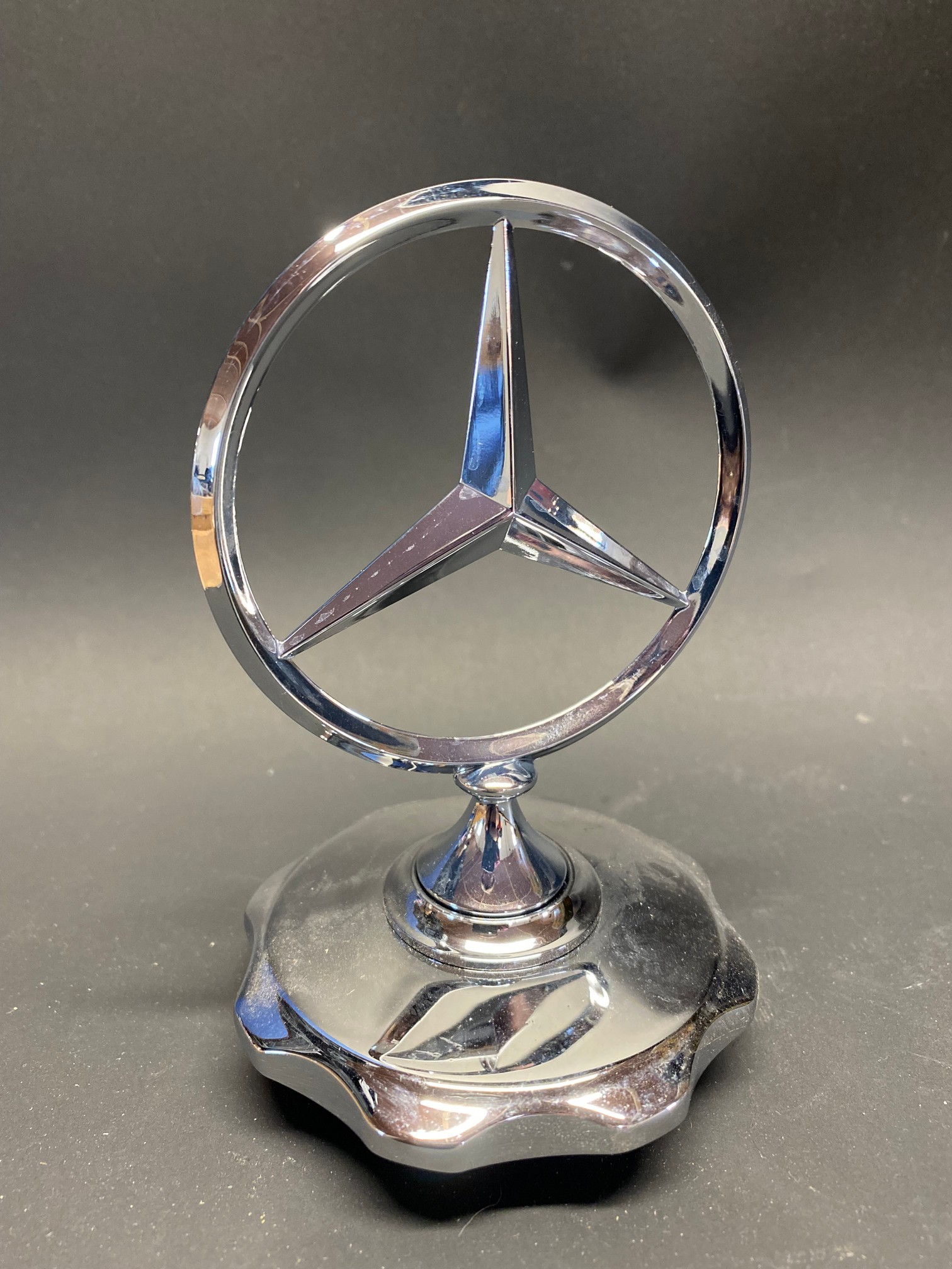 A Mercedes Benz star mascot, radiator cap base, appears new or unused.
