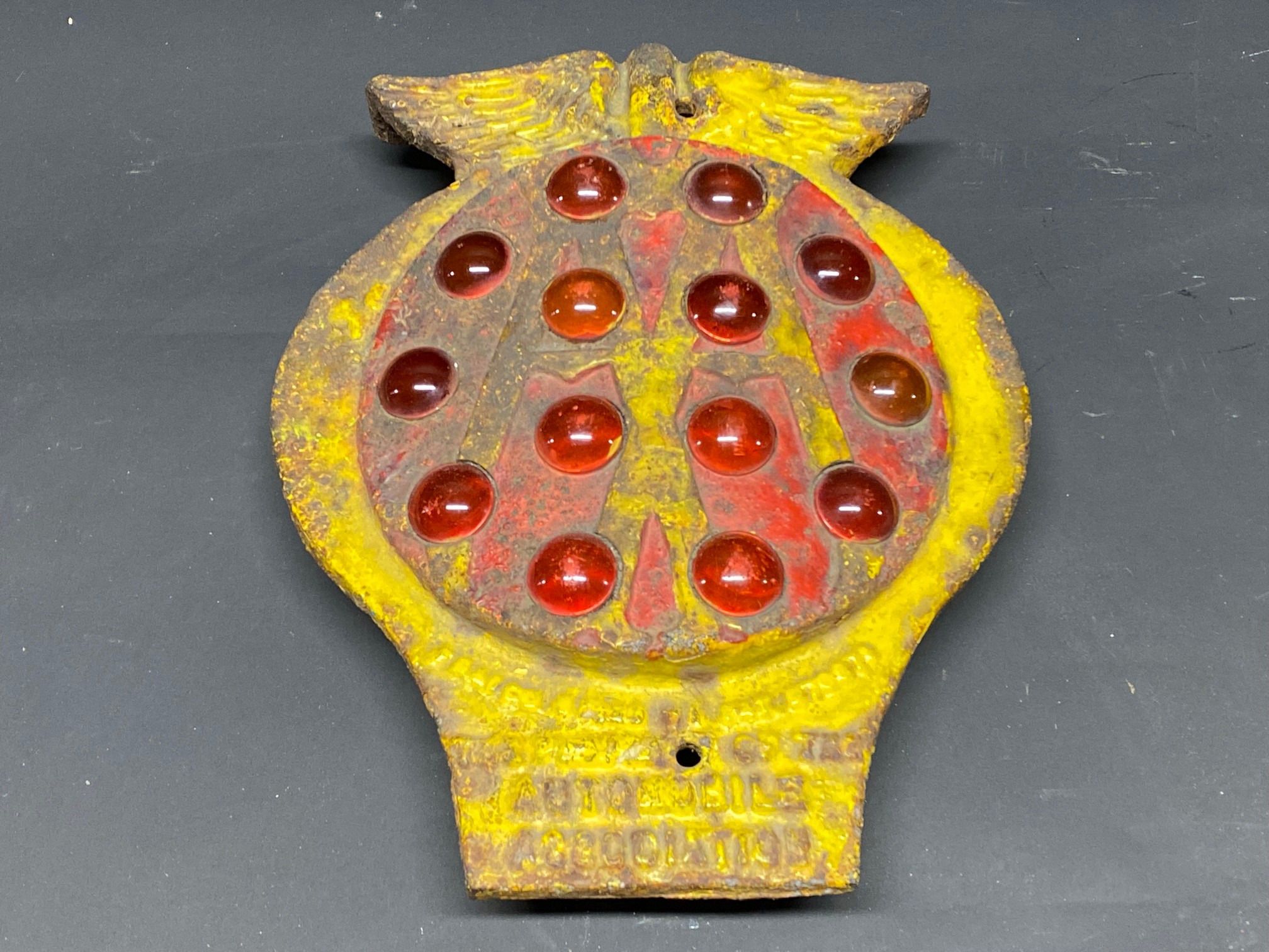 An early cast iron AA post mounted plaque inset with red glass eyes.
