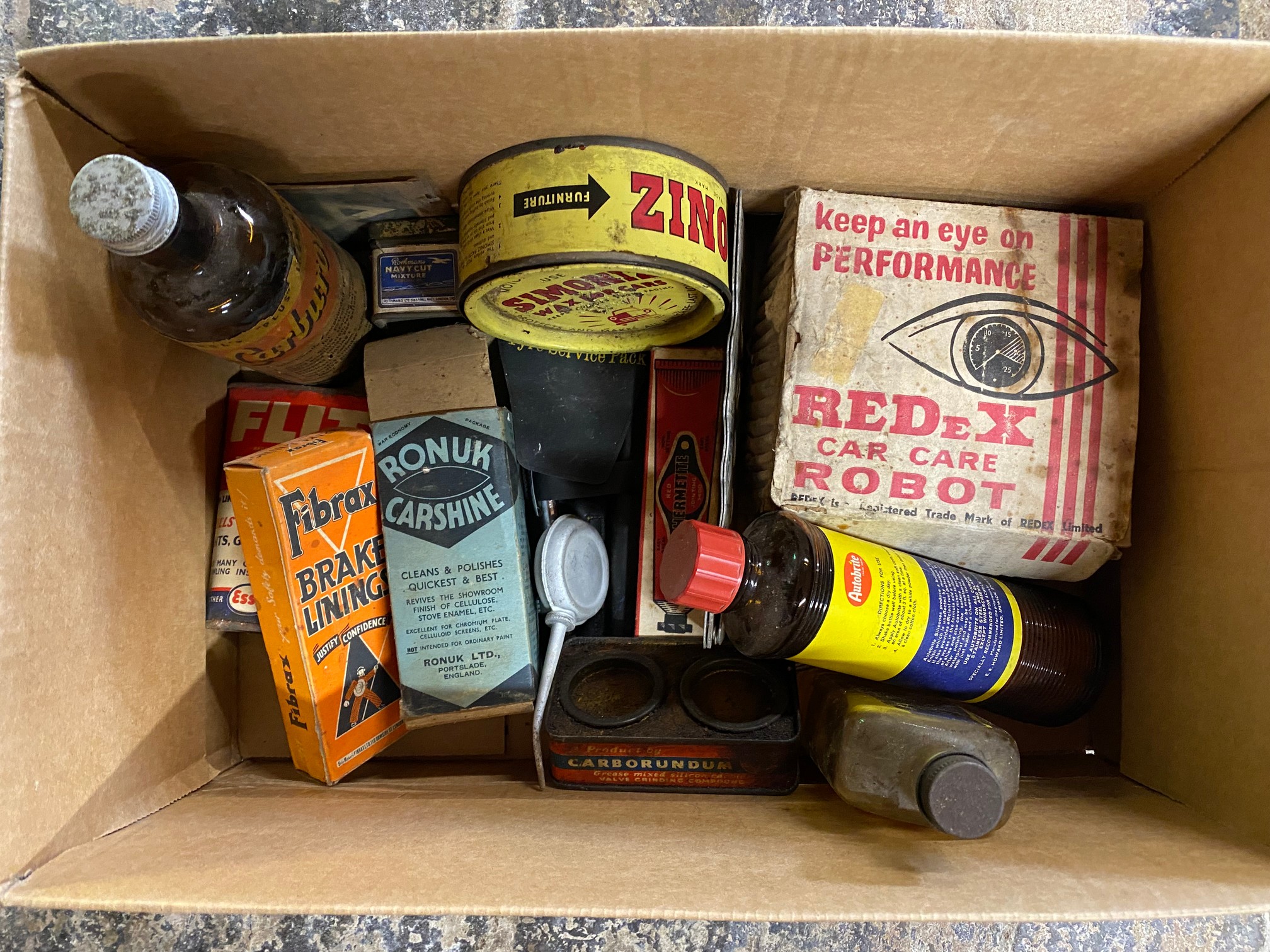 A box of assorted motoring packaging and collectables, also an Esso Fan Belt plastic sign.