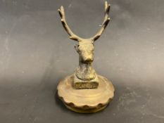 A polished brass accessory mascot in the form of a stag's head, mounted on a radiator cap.