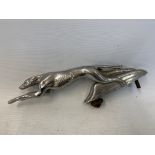 A car accessory mascot in the form of a stylised leaping greyhound, chrome plated finish.