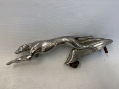 A car accessory mascot in the form of a stylised leaping greyhound, chrome plated finish.