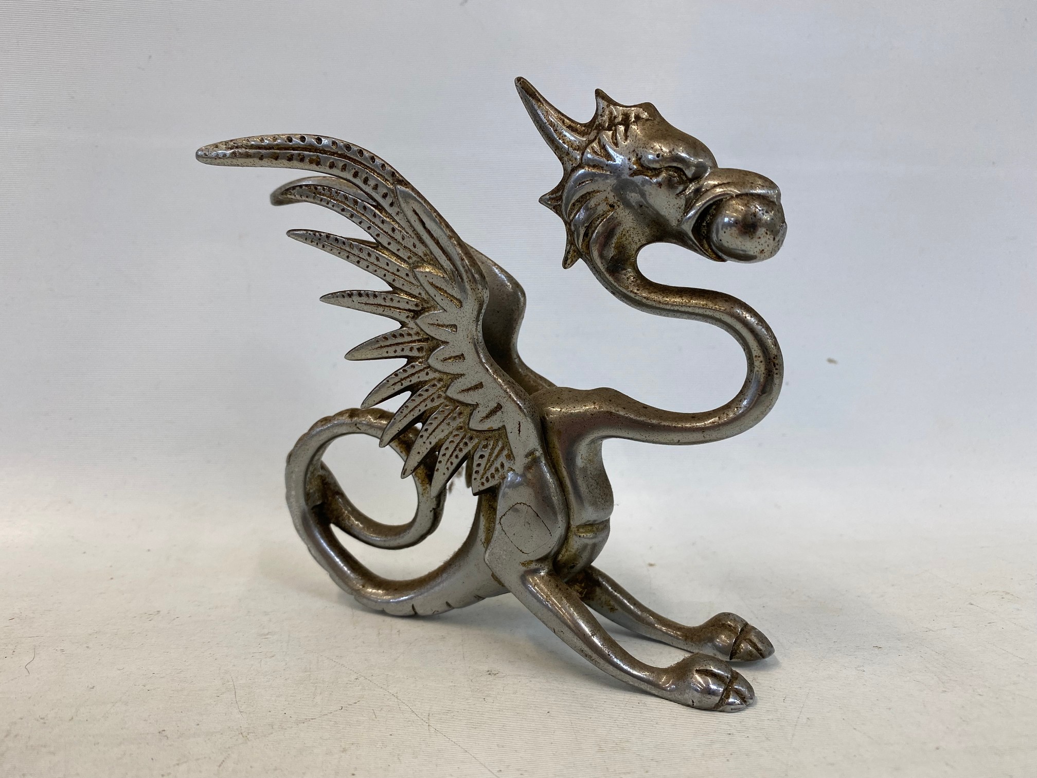 A chrome plated car mascot in the form of a griffin or dragon.