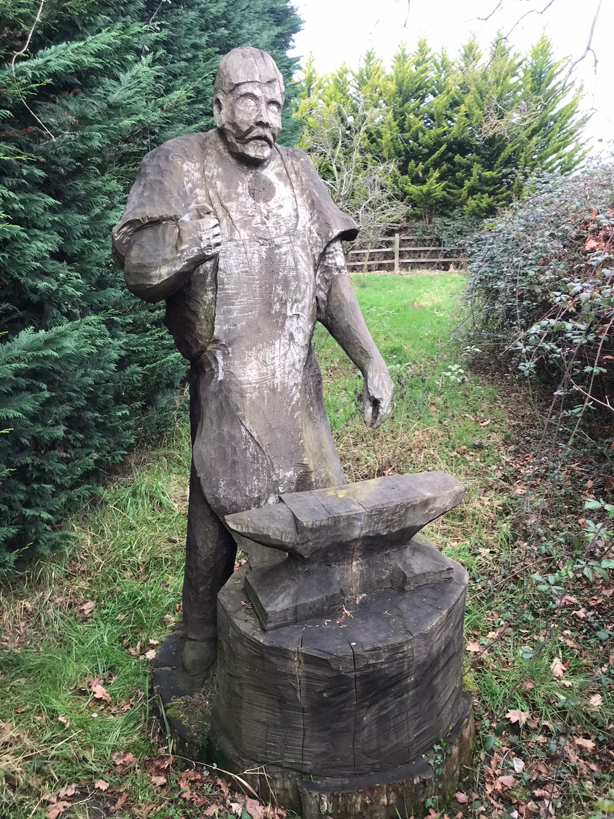 Carved wood statue of a blacksmith