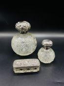 Two cut glass bottles with silver lids and a silver lidded dish
