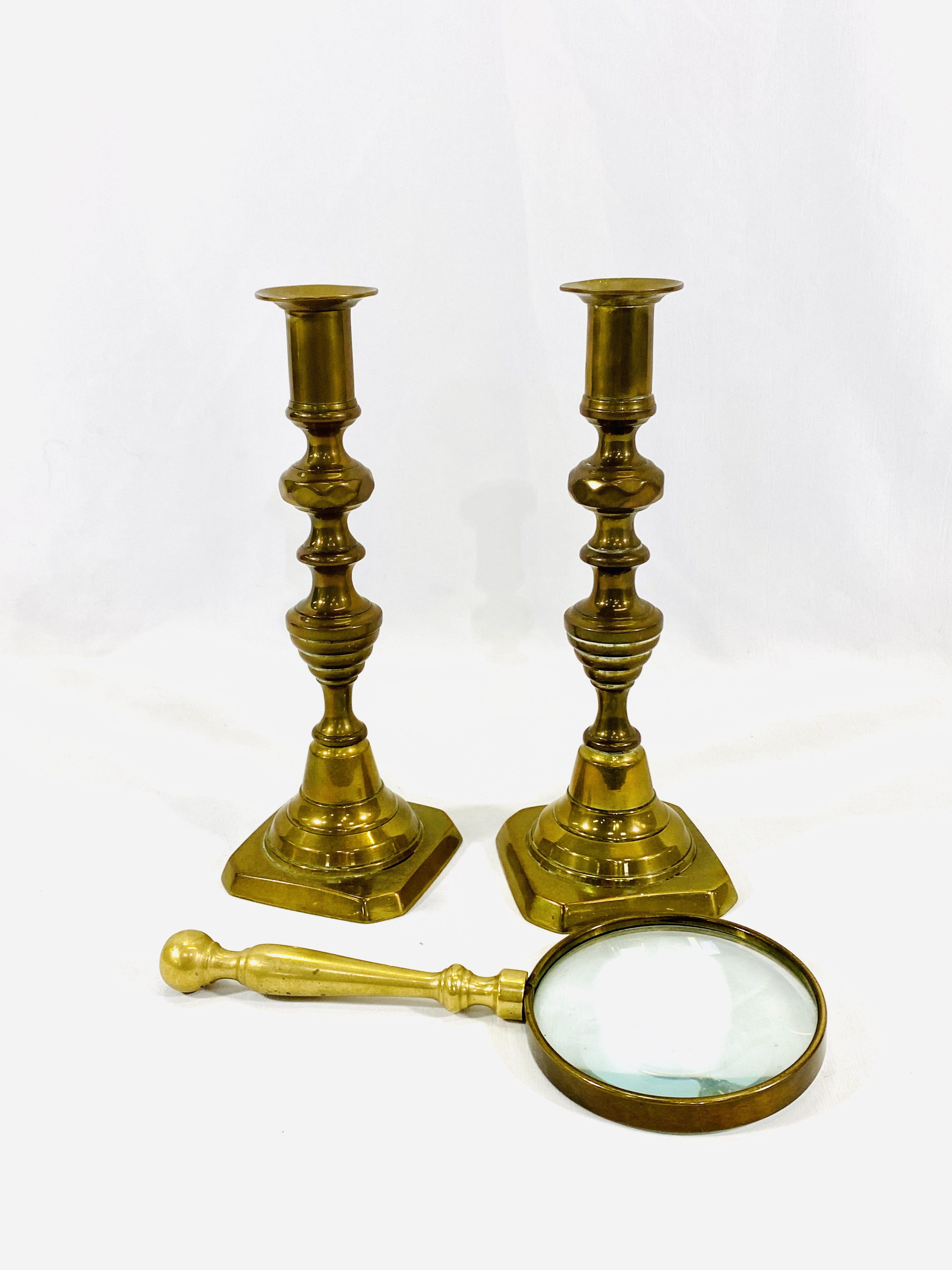 Pair of brass candlesticks and a brass magnifying glass