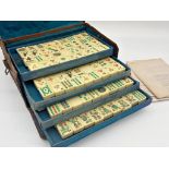 Antique Mah Jong set, in leather case enclosing five tiers on polychrome bone tiles, with four games