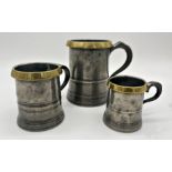 Set of three antique graduated pewter mugs with brass rims, quart pint and half pint, the quart