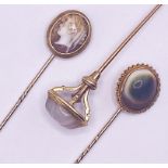 Three yellow metal stick pins set with a cameo of a classical maiden, a carved rock crystal