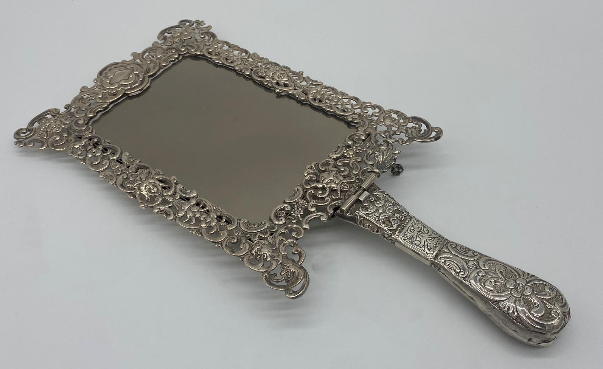 Remarkable late Victorian silver hand / easel mirror, the frame pierced with hinged handle,