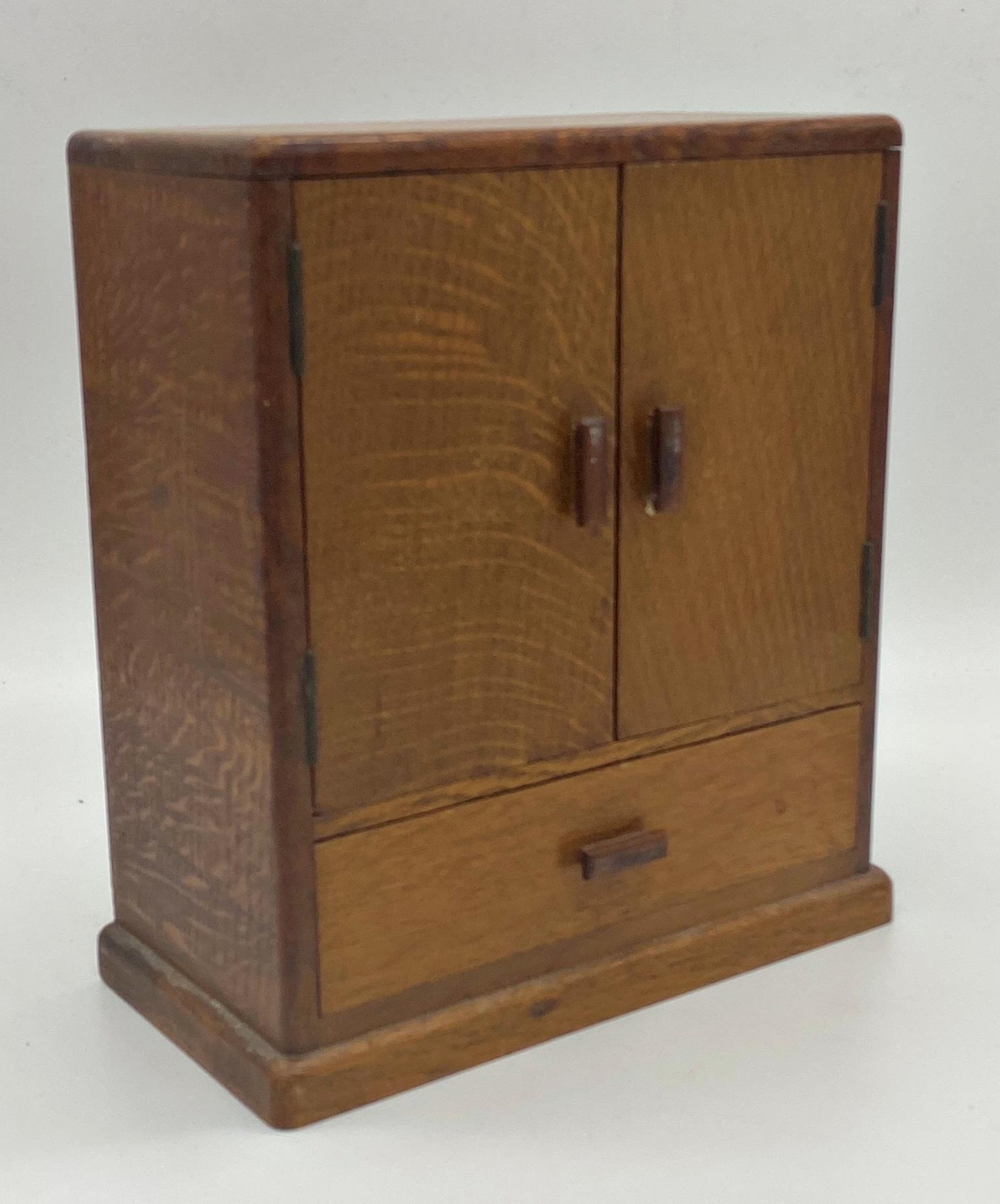 Art Deco fumed oak apprentice cabinet, twin doors enclosing a shelved interior over a single drawer,