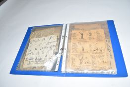 Blue ring binder containing a large collection of Tom Webster's cartoons for The Daily Mail, many