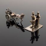 A Continental white metal miniature of a couple in a horse-drawn carriage, together with a miniature