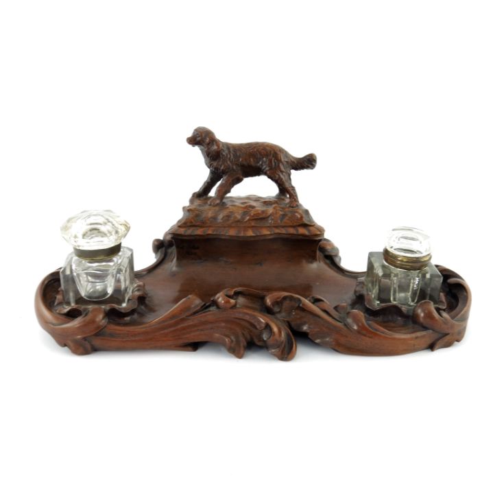 A late 19th Century Black Forest double desk inkwell, of serpentine form with high relief carved