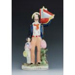 A Staffordshire figure of a ‘Sailor’, circa 1855, modelled standing, holding a ship with stripe pain