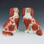 A pair of Staffordshire pottery dogs, circa 1860, modelled as seated King Charles spaniels, iron red