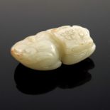 A Chinese pale jade netsuke, in the form of a recumbent stylized shishi, 5.5cm wide