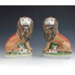 A pair of Staffordshire pottery Lion and Lamb figures, circa 1860, modelled seated with a lamb, on a