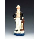 A Staffordshire figure of Joseph John Gurney, circa 1850, modelled standing at a plinth, wearing a b