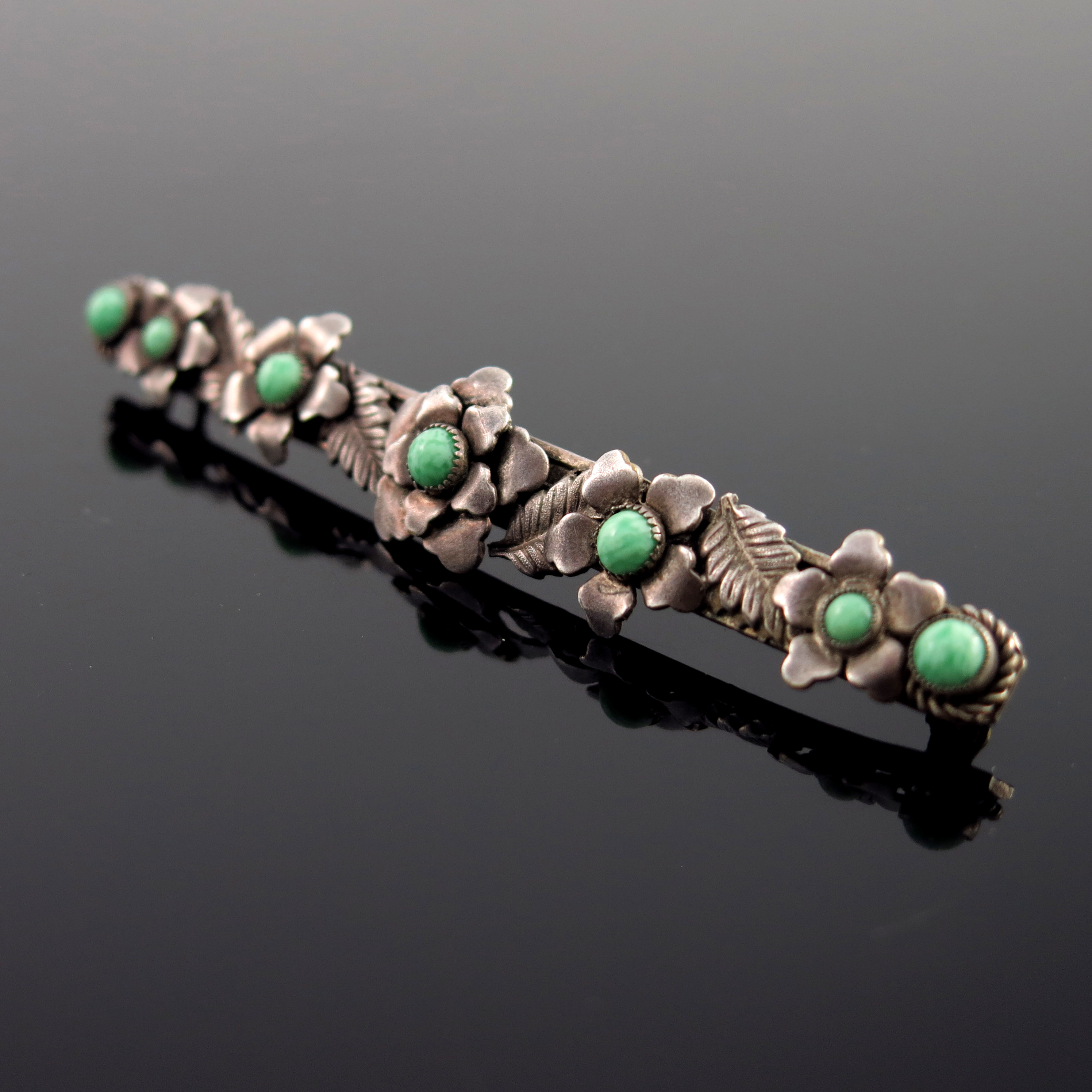 An Arts and Crafts white metal and green cabochon brooch, circa 1940s, bar form with applied
