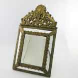 A 19th Century easel looking glass of Baroque design, cushion form with pediment, pressed brass